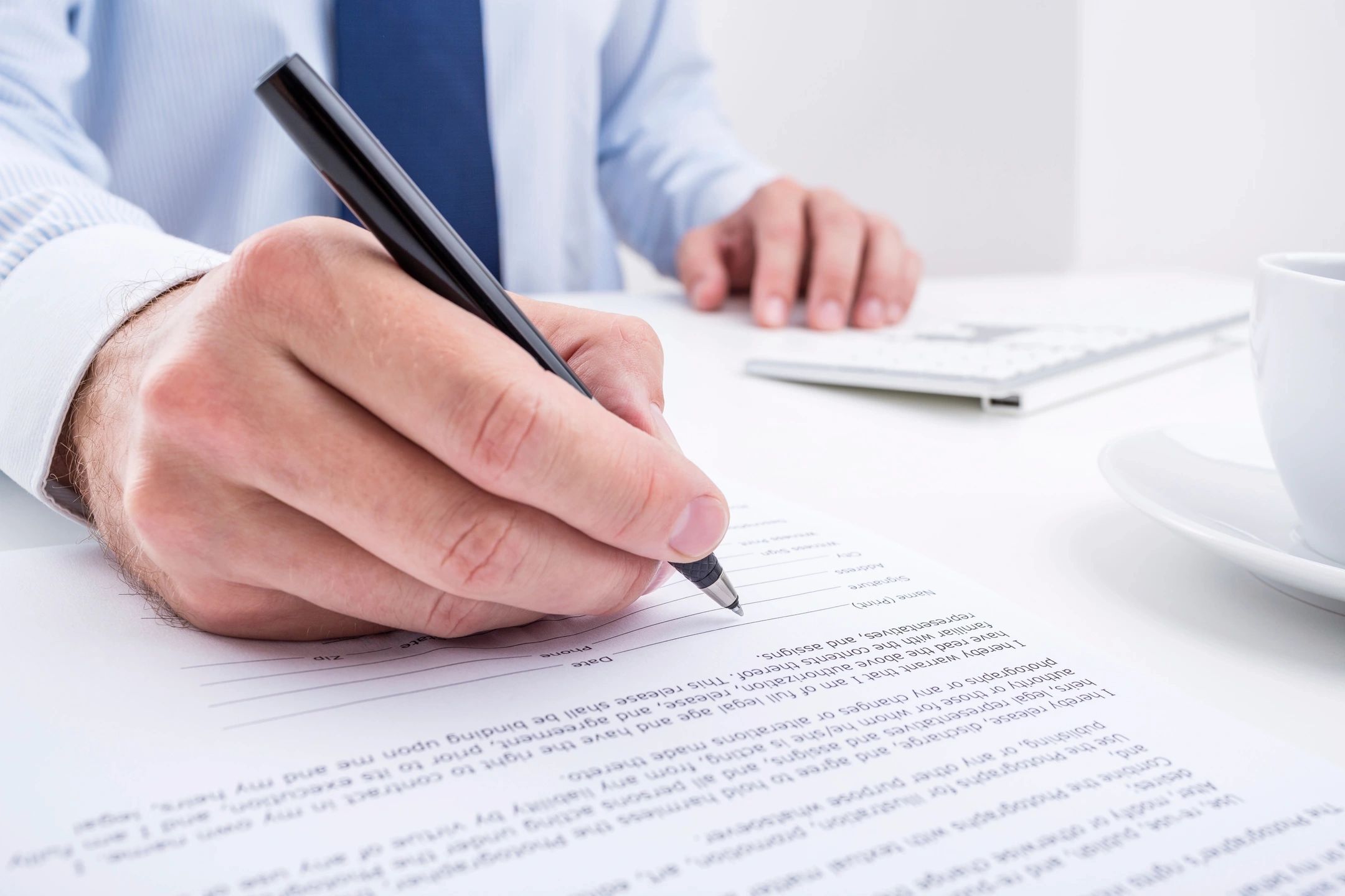 Hand holding a pen signing a document/contact